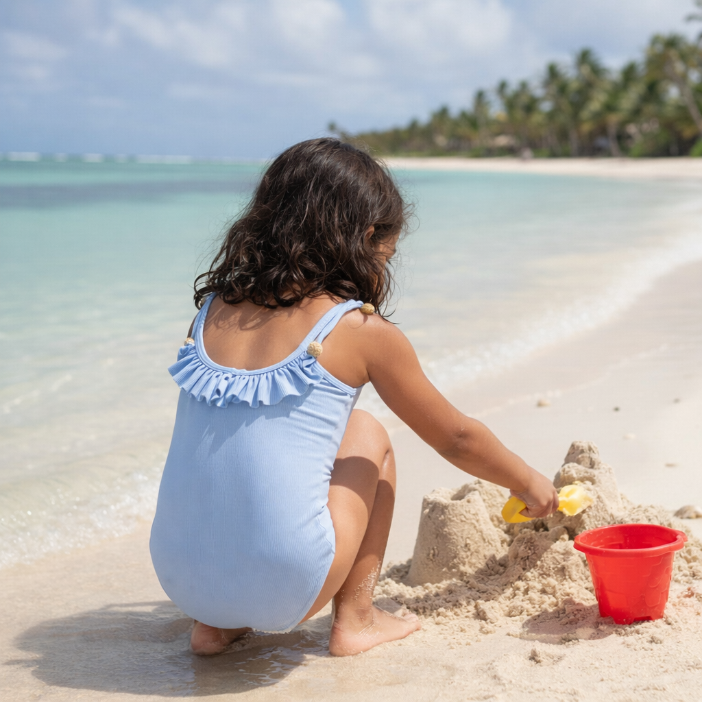 Designer Iris Swimsuit for girls in blue with sea shell charms on side ties, ruffled design, customized fit and plus sizes. Comfortable swimwear for kids holiday outings.